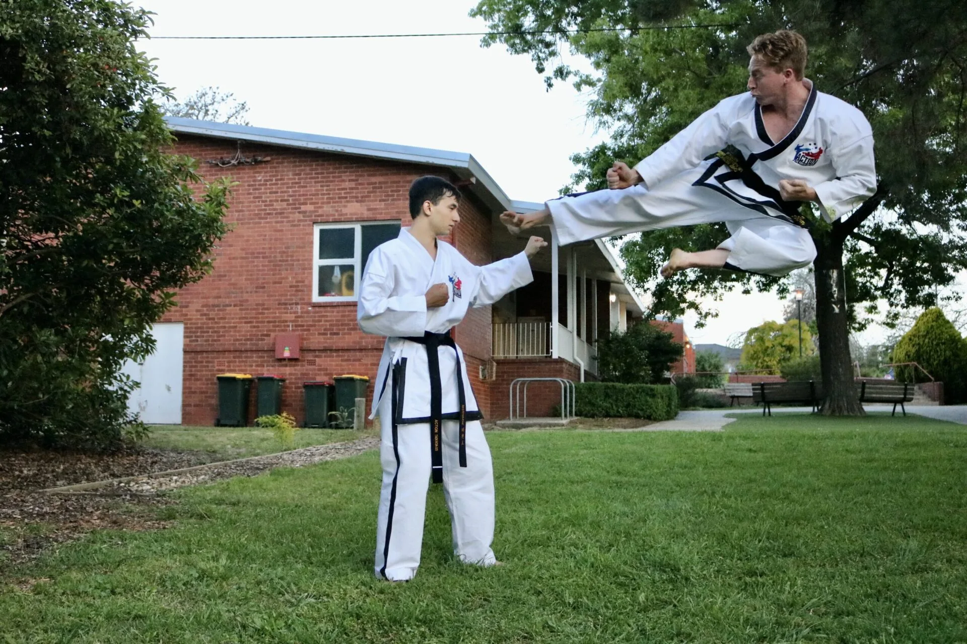 Chief Instructor Alex Benson flying side kick outside with Instructor Alfred Ding.